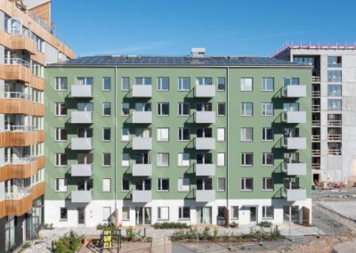 Hyreslägenhetshus med solceller på taket, grön fasad och balkonger